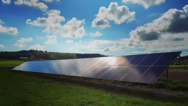 Lång rad solpaneler fångar solljuset under en molnig himmel. Solkraft EMK AB bidrar till en grönare framtid.